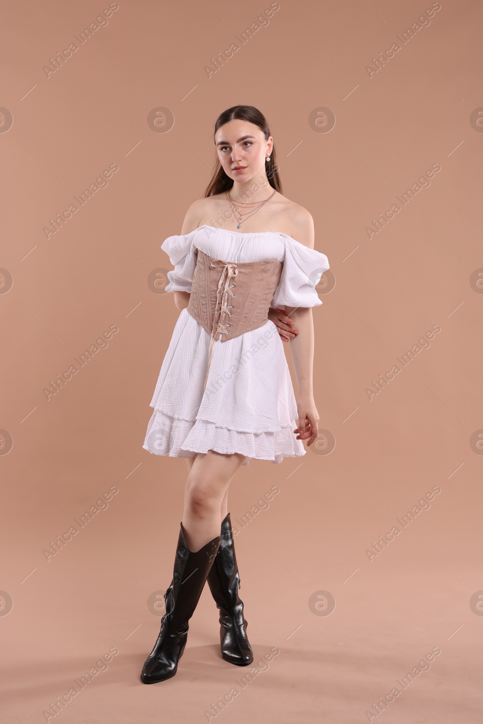 Photo of Beautiful woman in velvet corset posing on beige background
