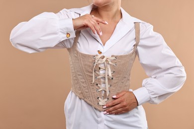 Woman in stylish corset on beige background, closeup