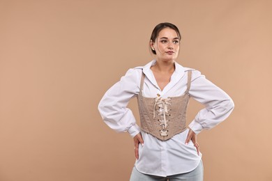 Beautiful woman in stylish corset posing on beige background. Space for text
