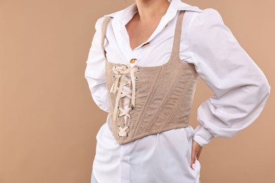 Woman in stylish corset on beige background, closeup