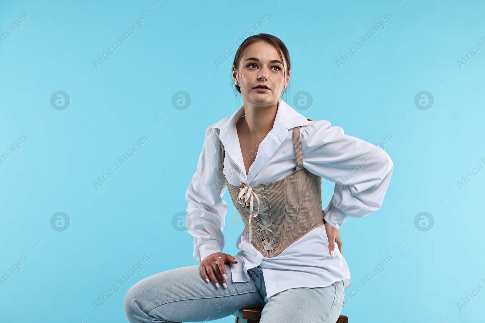 Photo of Beautiful woman in stylish corset on light blue background