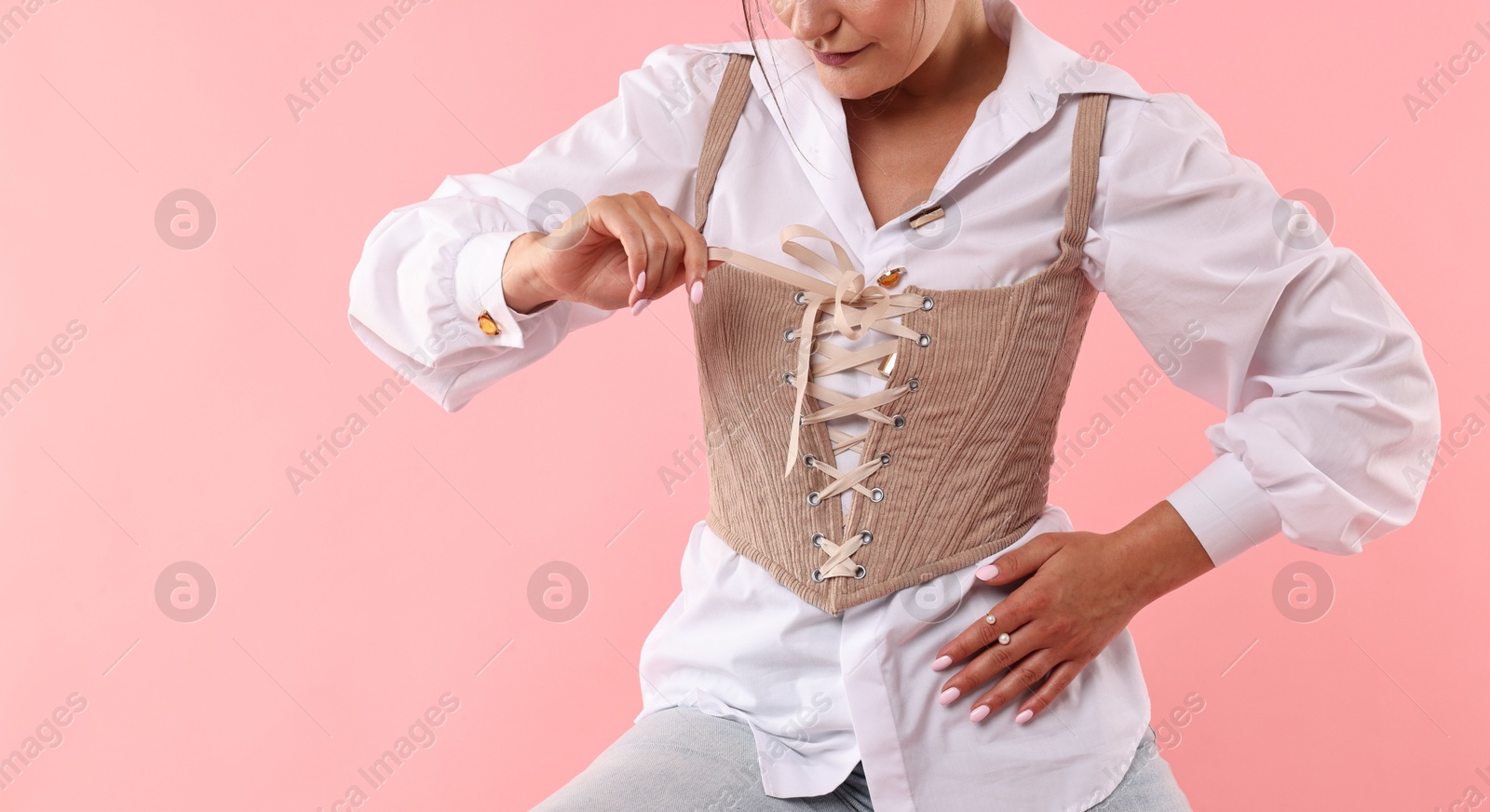 Photo of Woman in stylish corset on pink background, closeup