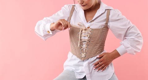 Woman in stylish corset on pink background, closeup