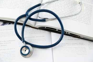 Photo of One new medical stethoscope and books on table, above view