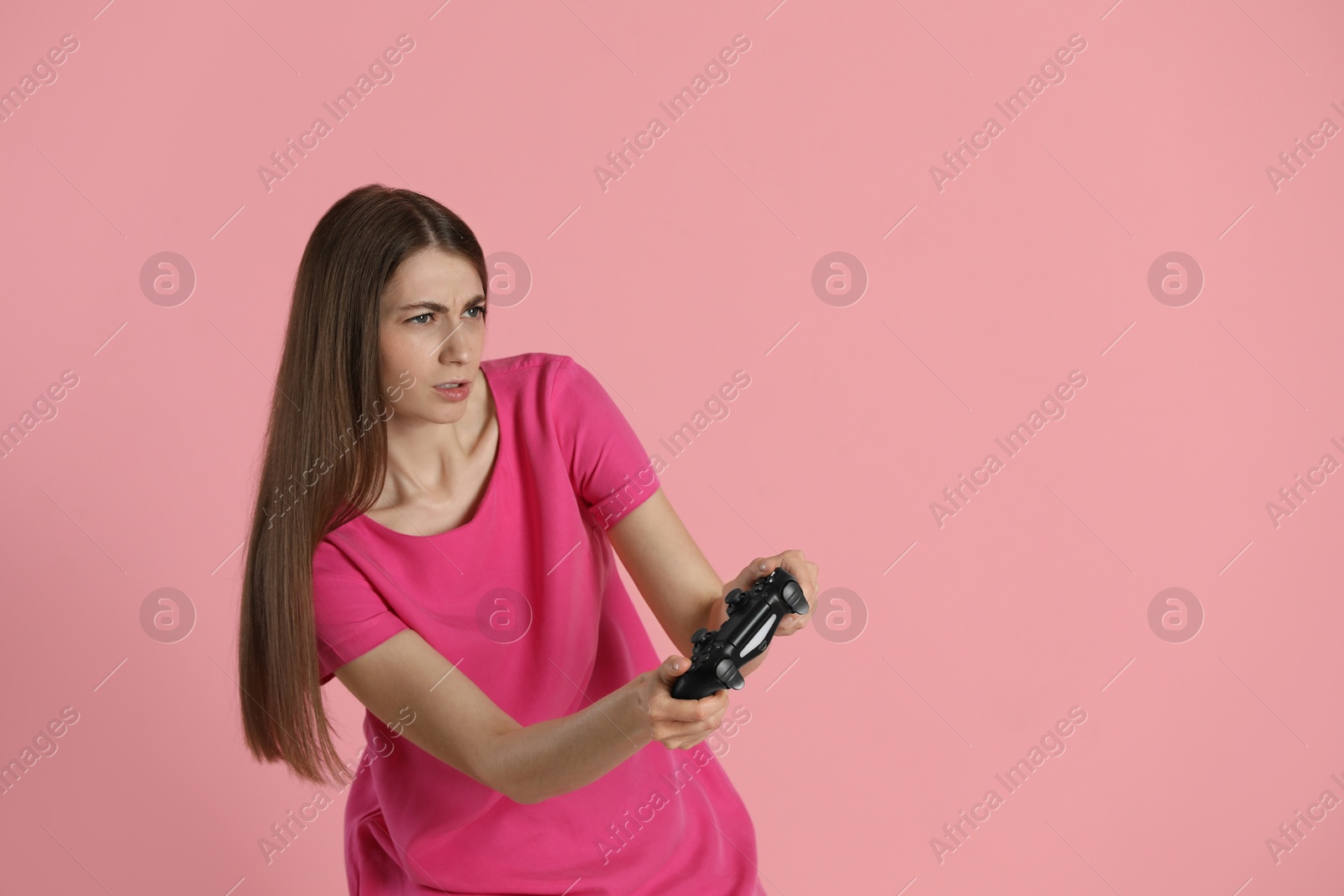 Photo of Woman playing video games with controller on pink background, space for text