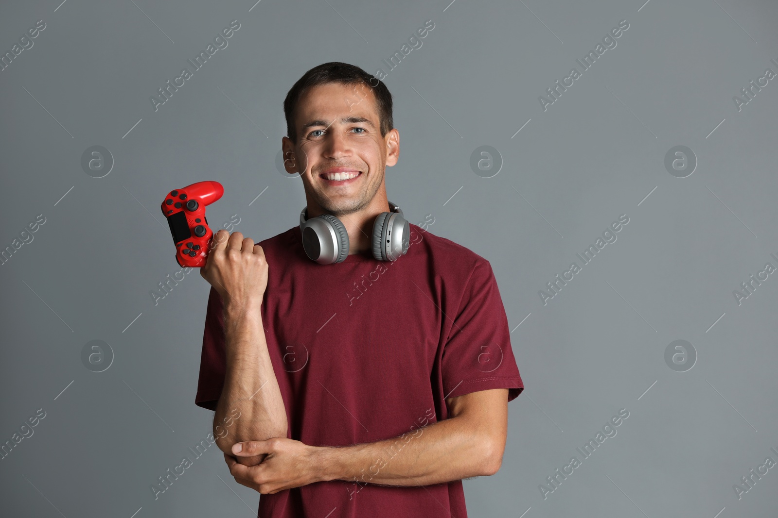 Photo of Happy man in headphones with controller on gray background