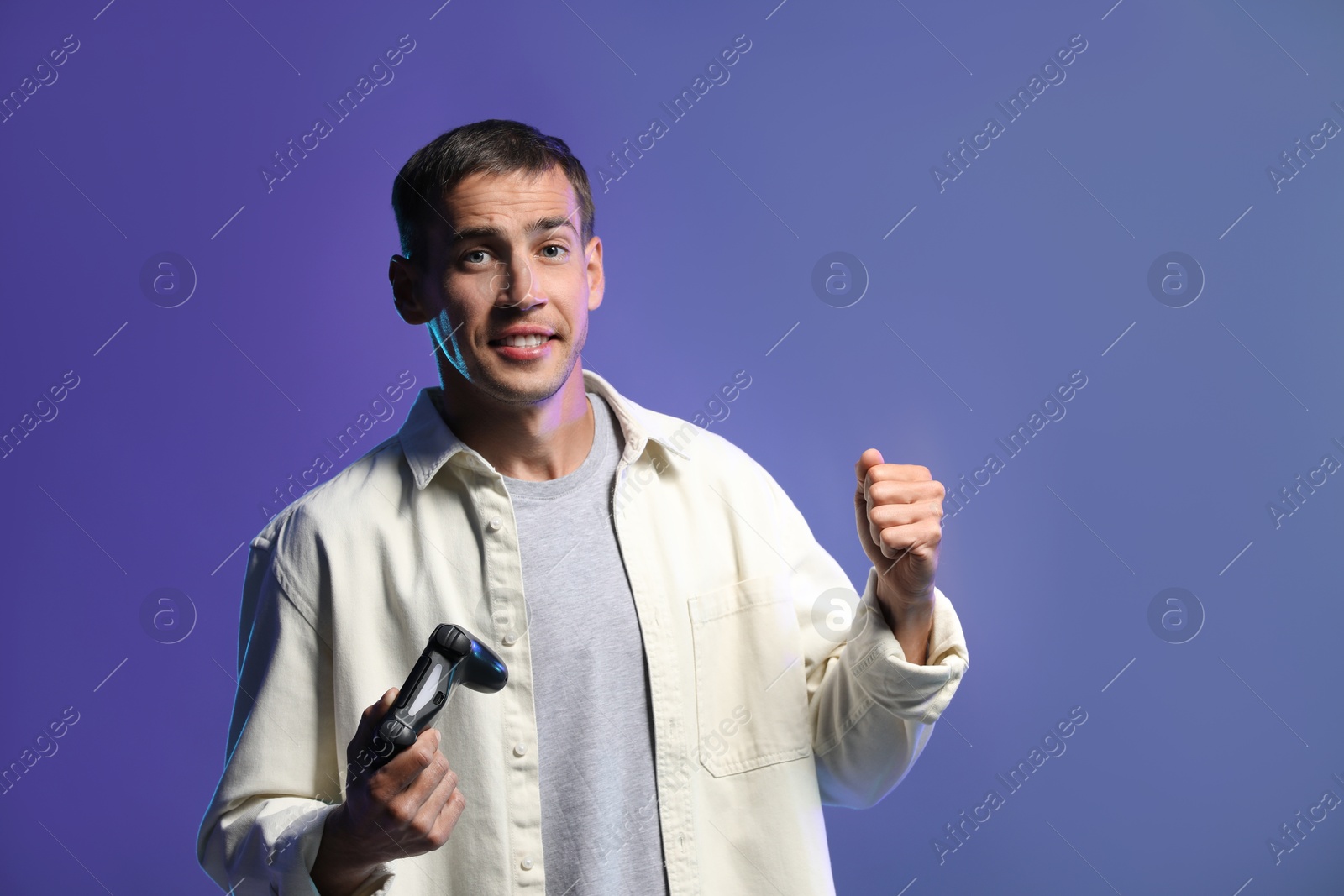 Photo of Happy man with controller on violet background