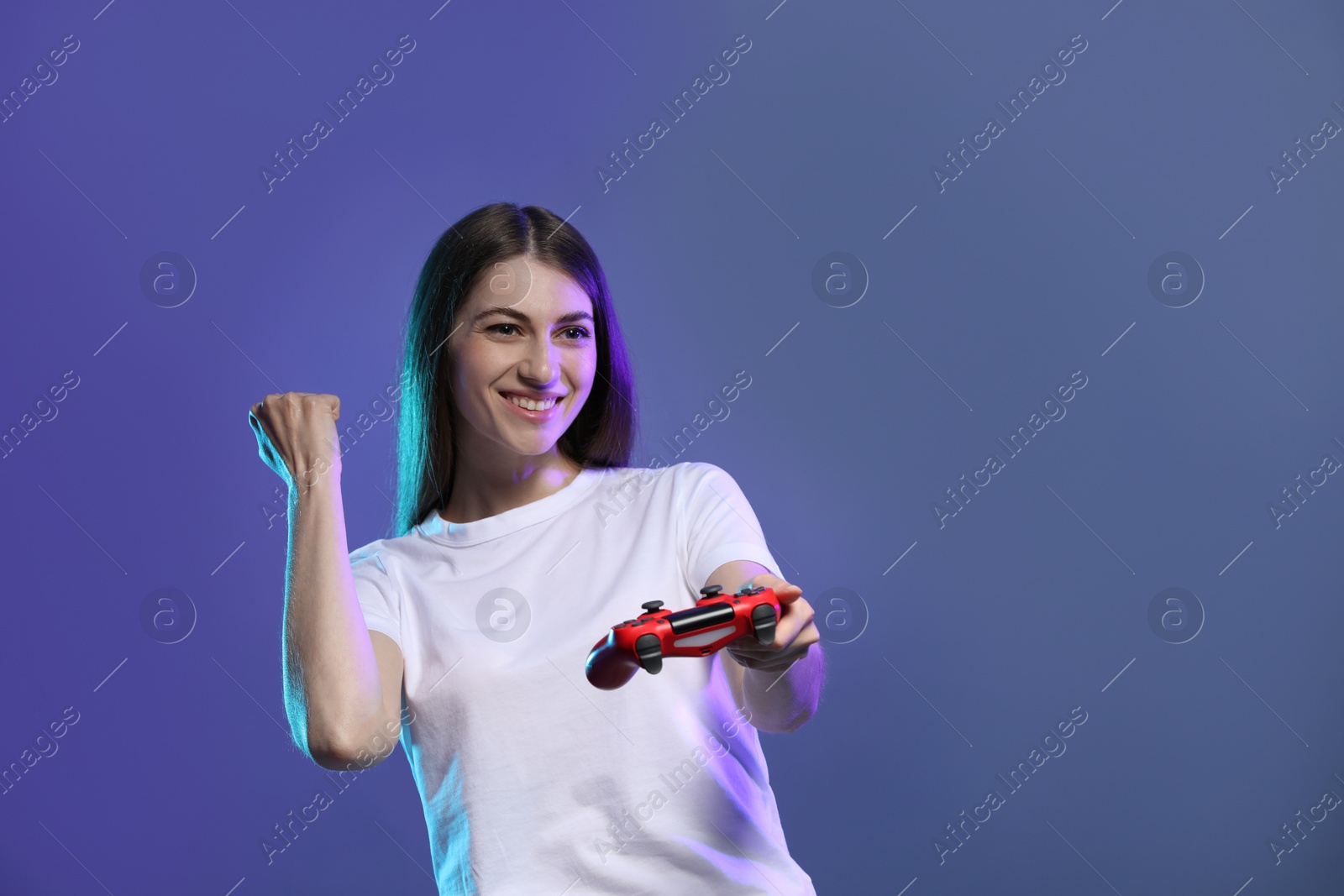 Photo of Happy woman with controller on violet background, space for text