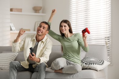 Couple playing video games with controllers at home