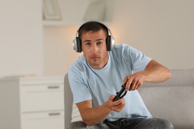 Man in headphones playing video games with joystick at home