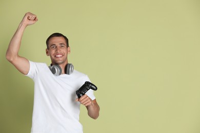 Photo of Happy man with controller on light green background, space for text