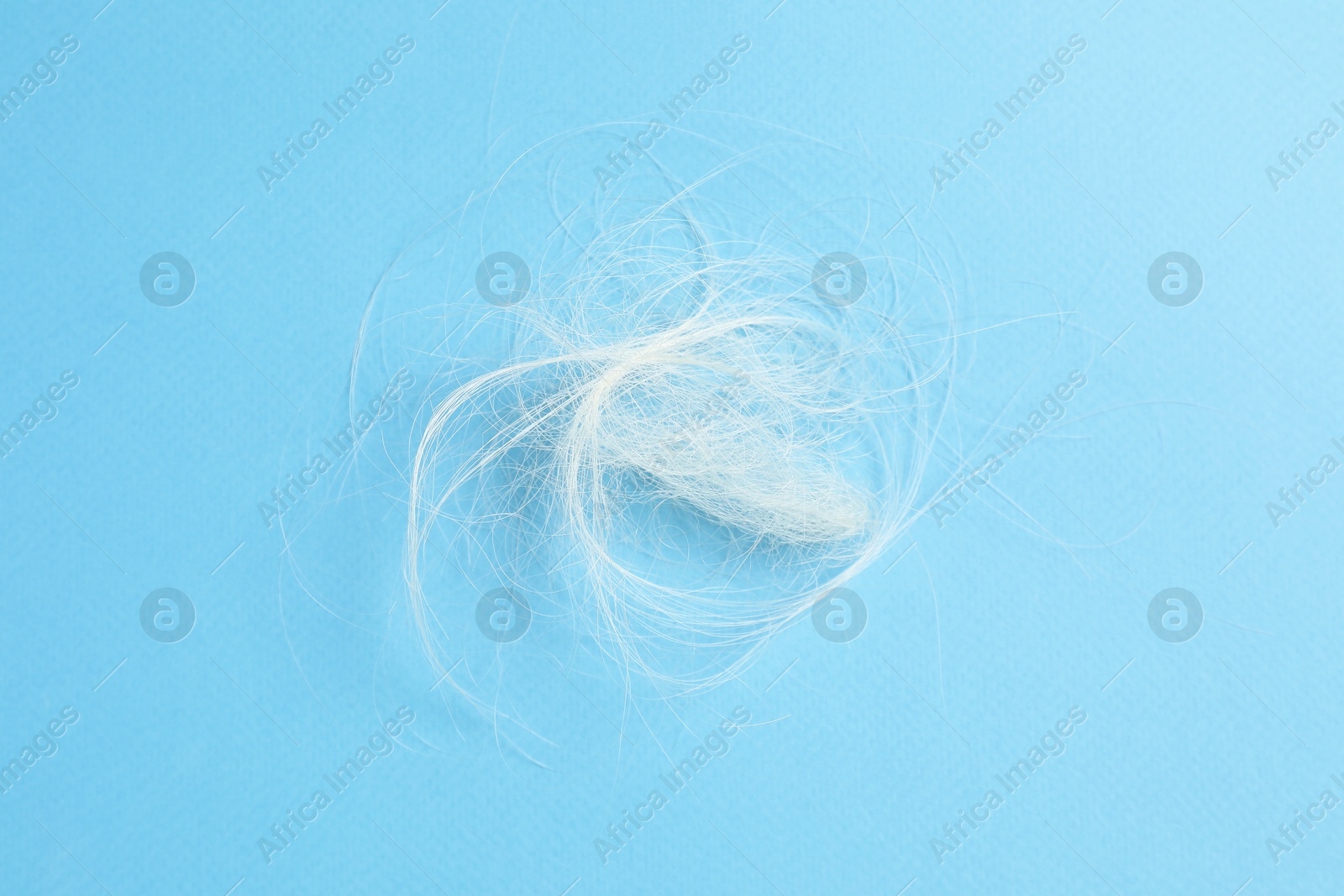 Photo of Pile of lost hair on light blue background, top view