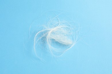 Photo of Pile of lost hair on light blue background, top view