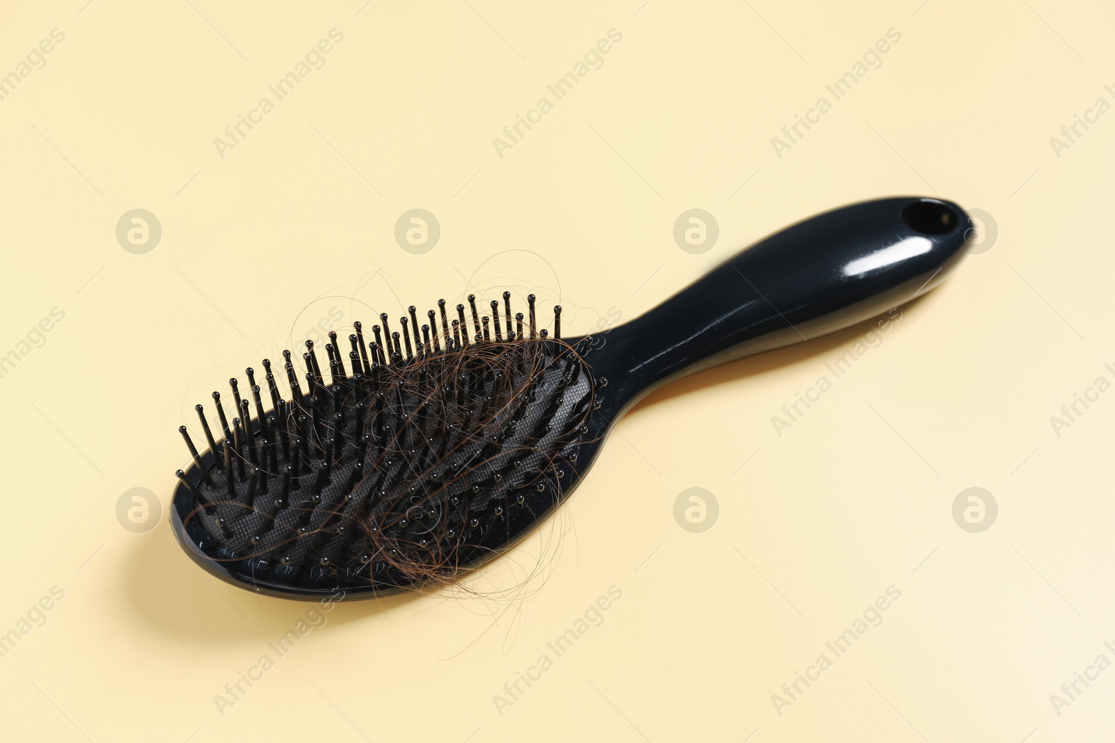 Photo of Brush with lost hair on yellow background