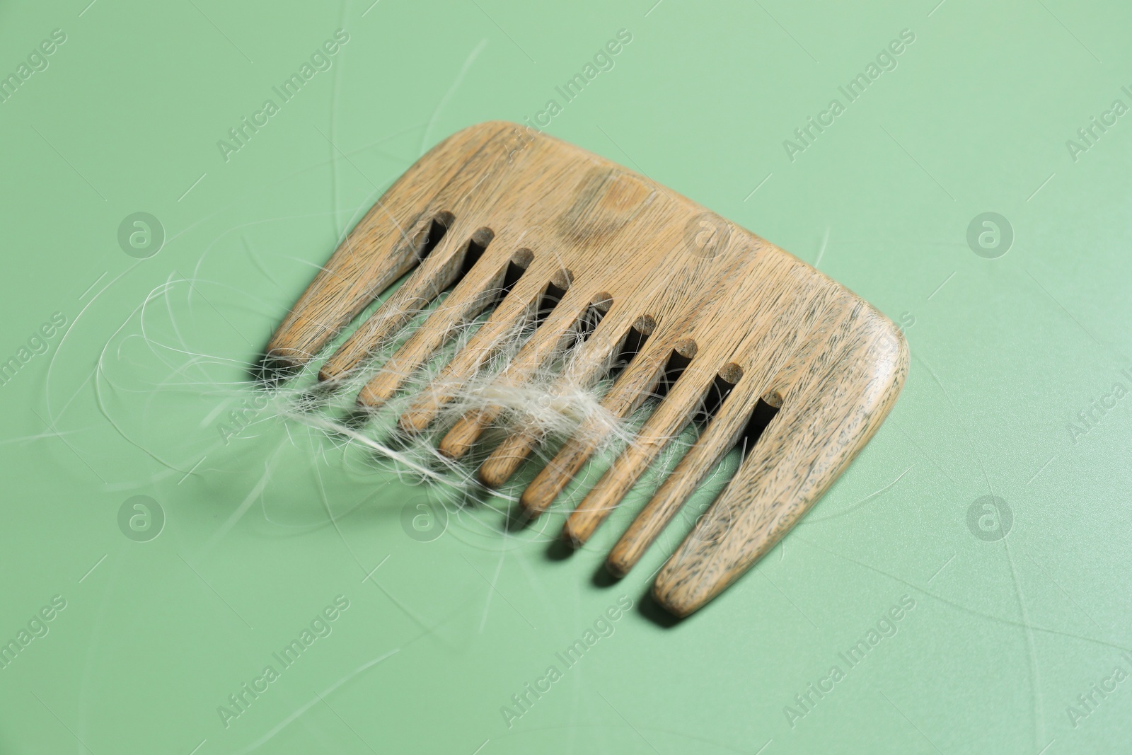 Photo of Comb with lost hair on green background