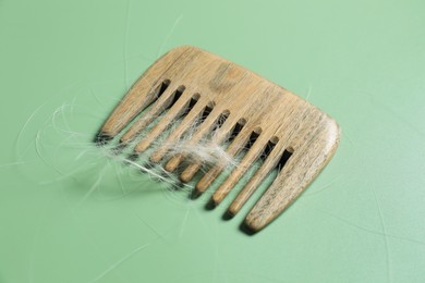 Photo of Comb with lost hair on green background