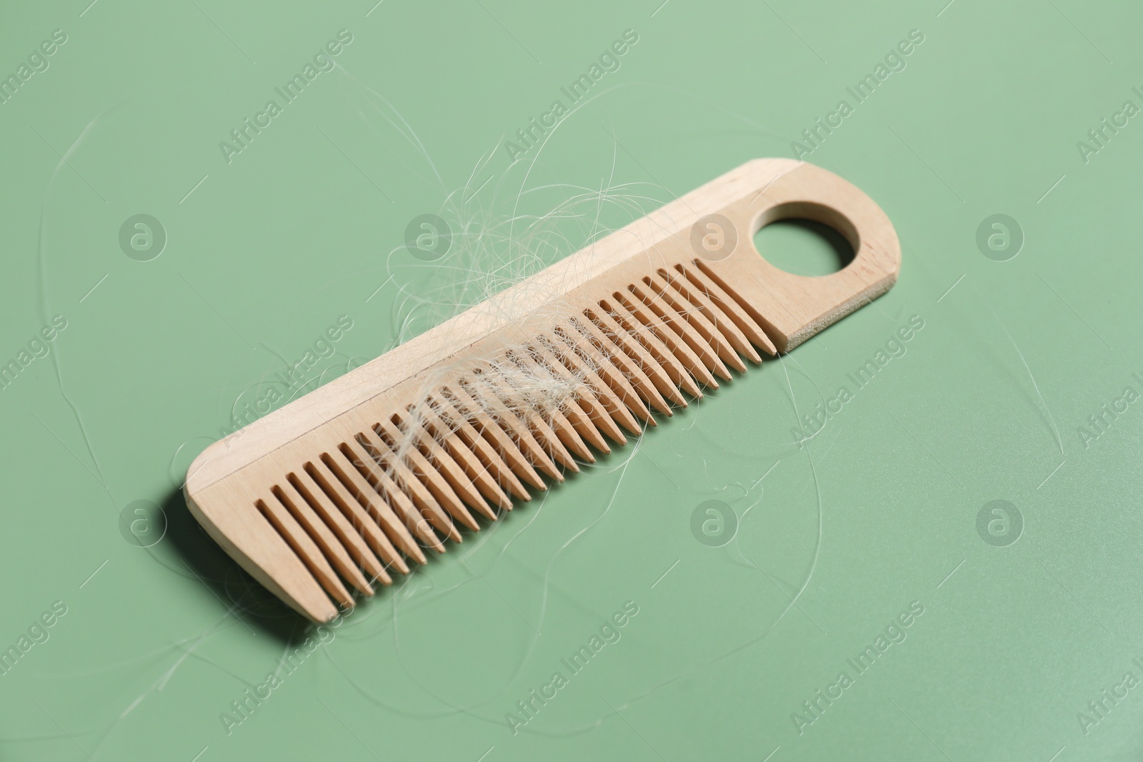 Photo of Wooden comb with lost hair on green background