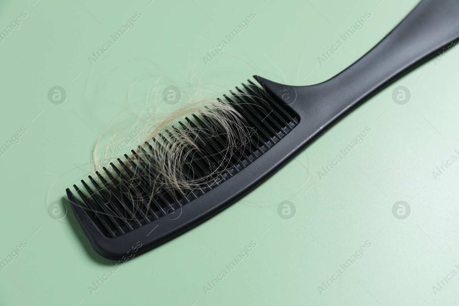 Photo of Comb with lost hair on green background