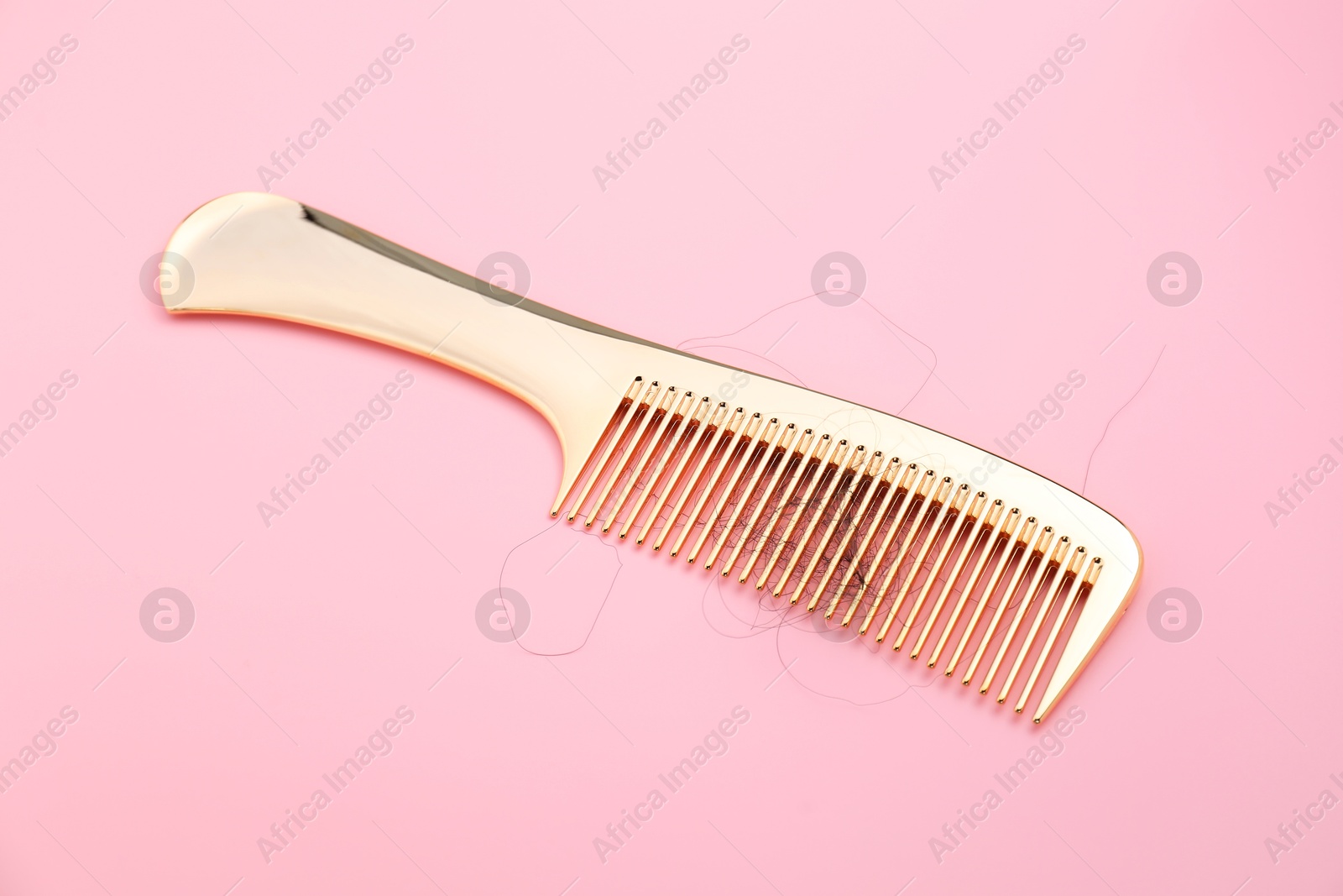 Photo of Comb with lost hair on pink background