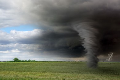 Green meadow with coming thunderstorm and tornado. Weather changes