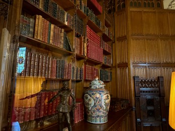 Utrecht, Netherlands - June 17, 2024: Bookcase with old books, antique vase and bronze statue of Henry IV as child in De Haar castle