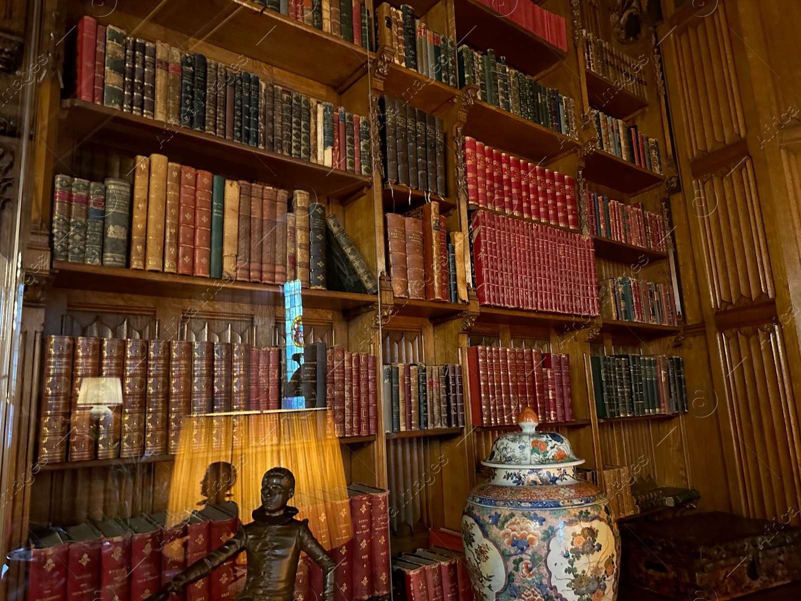 Photo of Utrecht, Netherlands - June 17, 2024: Bookcase with old books, antique vase and bronze statue of Henry IV as child in De Haar castle
