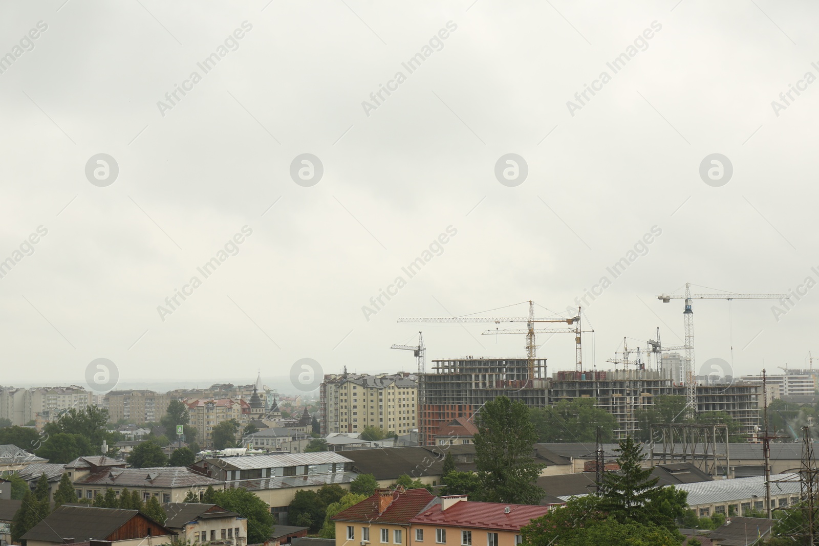 Photo of Picturesque view of city with buildings and construction cranes on cloudy day