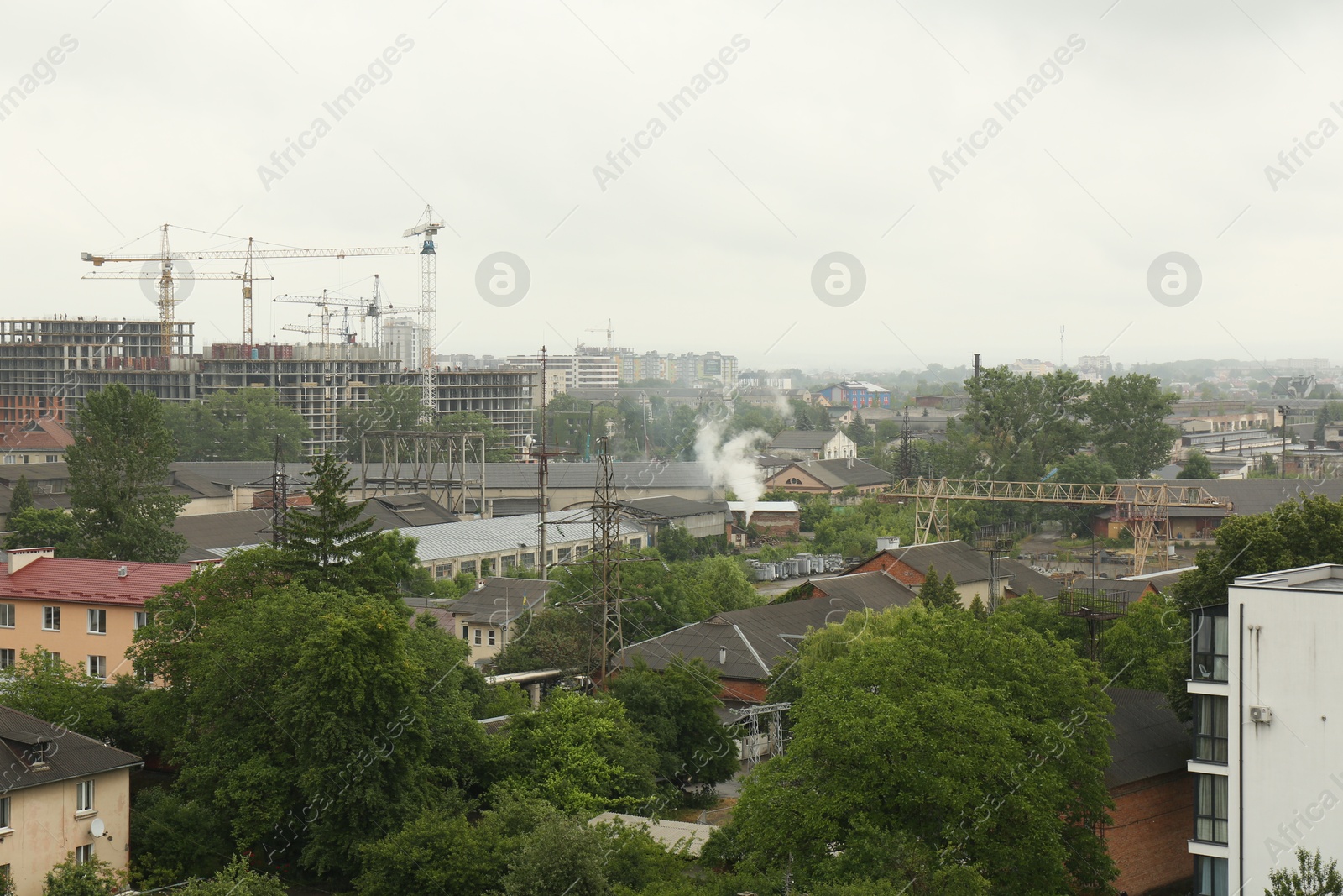 Photo of Picturesque view of city with buildings and construction cranes on cloudy day