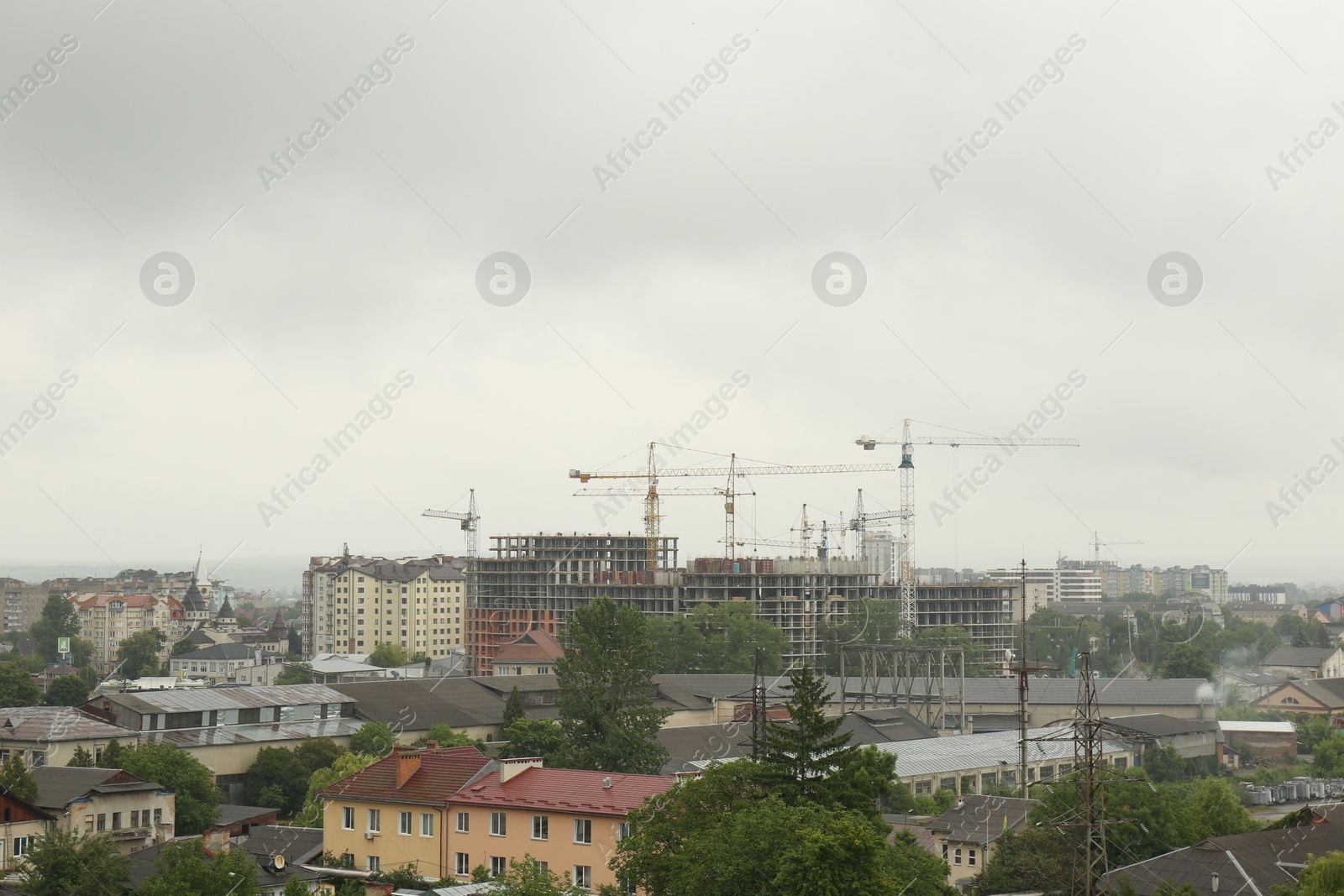Photo of Picturesque view of city with buildings and construction cranes on cloudy day