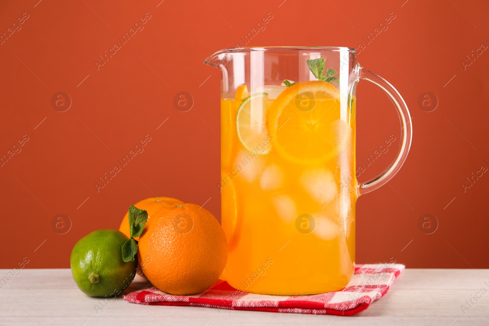 Photo of Freshly made lemonade in jug and citrus fruits on light wooden table