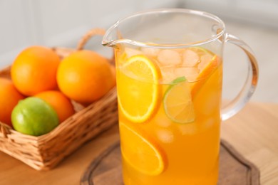 Photo of Freshly made lemonade in jug and citrus fruits on table