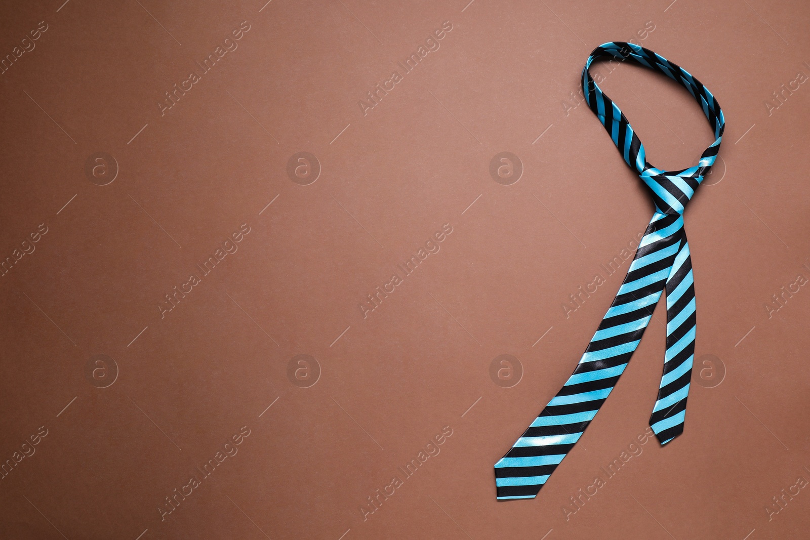 Photo of One striped necktie on brown background, top view. Space for text