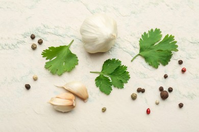 Fresh coriander leaves, garlic and peppercorns on light textured table, flat lay