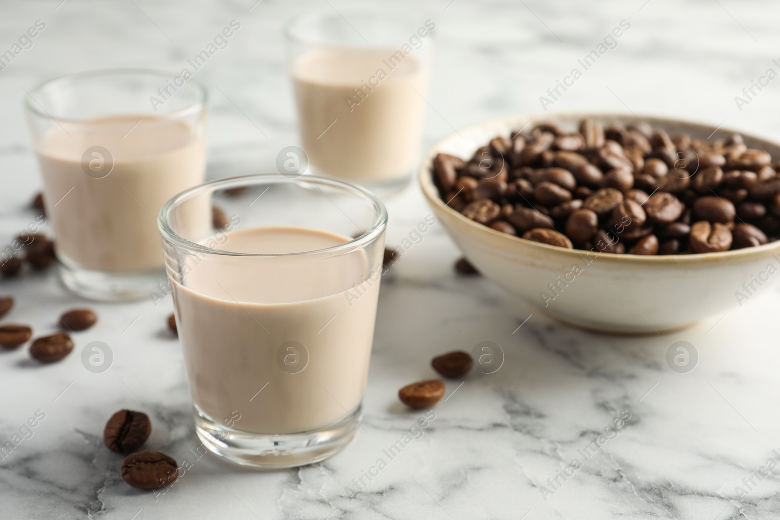 Photo of Coffee cream liqueur in glasses and beans on white marble table