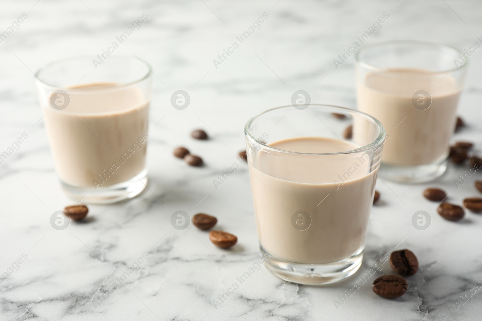 Photo of Coffee cream liqueur in glasses and beans on white marble table