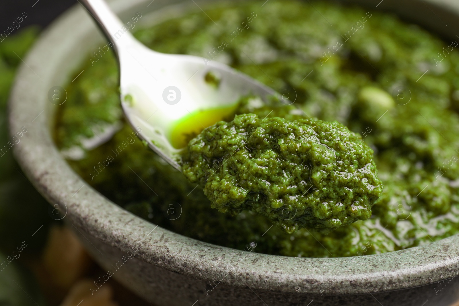 Photo of Taking tasty pesto sauce at table, closeup