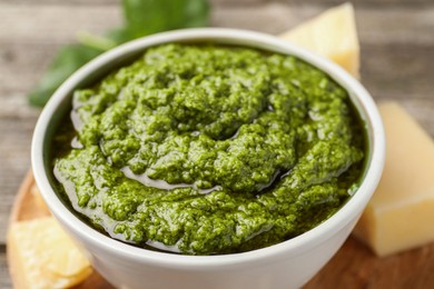 Tasty pesto sauce in bowl on table, closeup