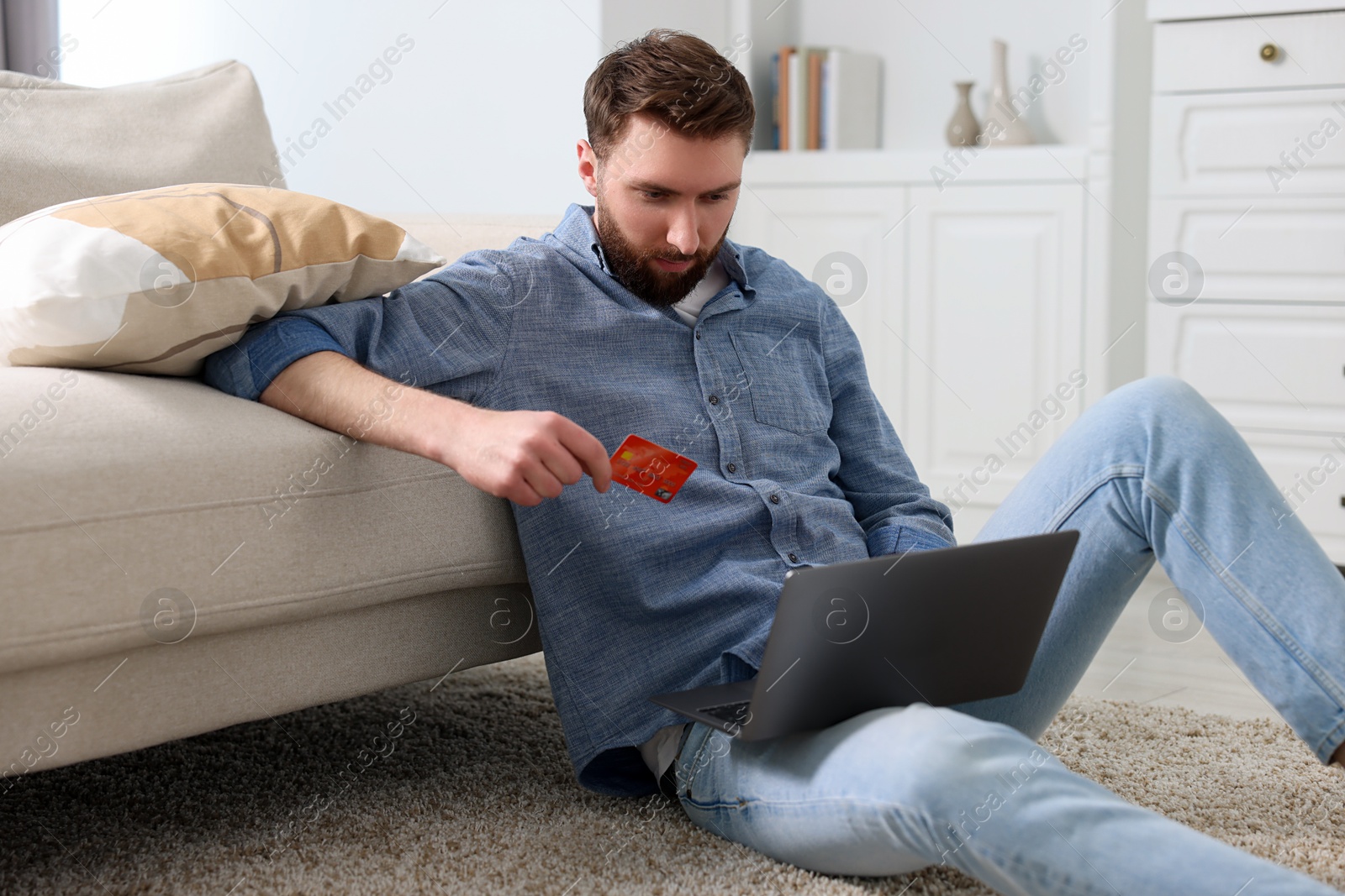 Photo of Online banking. Young man with credit card and laptop paying purchase at home