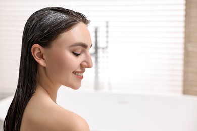 Smiling woman with applied hair mask in bathroom. Space for text