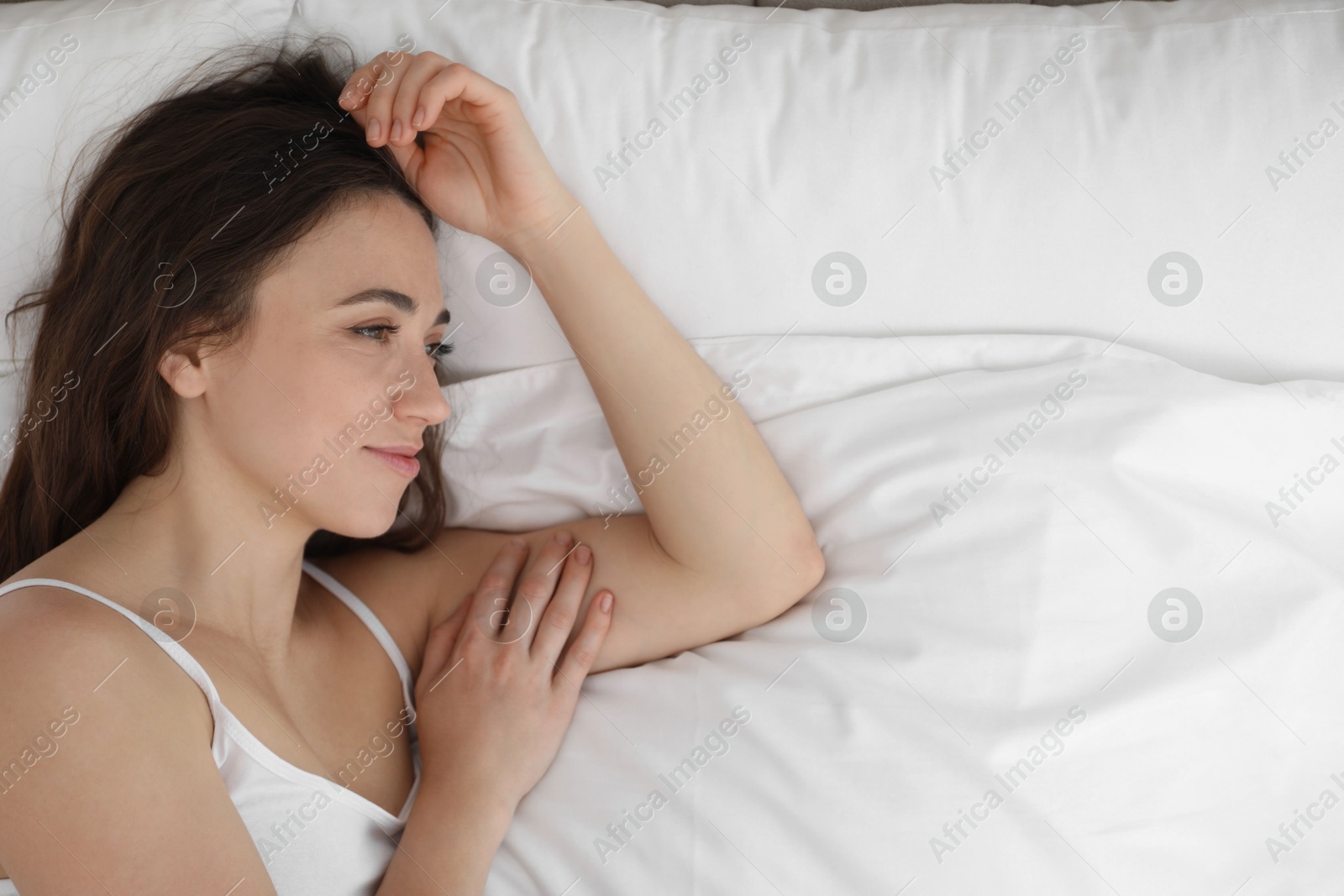 Photo of Beautiful woman lying on bed in morning, top view. Space for text