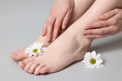 Closeup view of woman`s groomed feet after care procedure and beautiful flowers on grey background