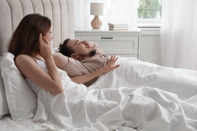 Bedtime. Irritated woman near her snoring husband in bed at home