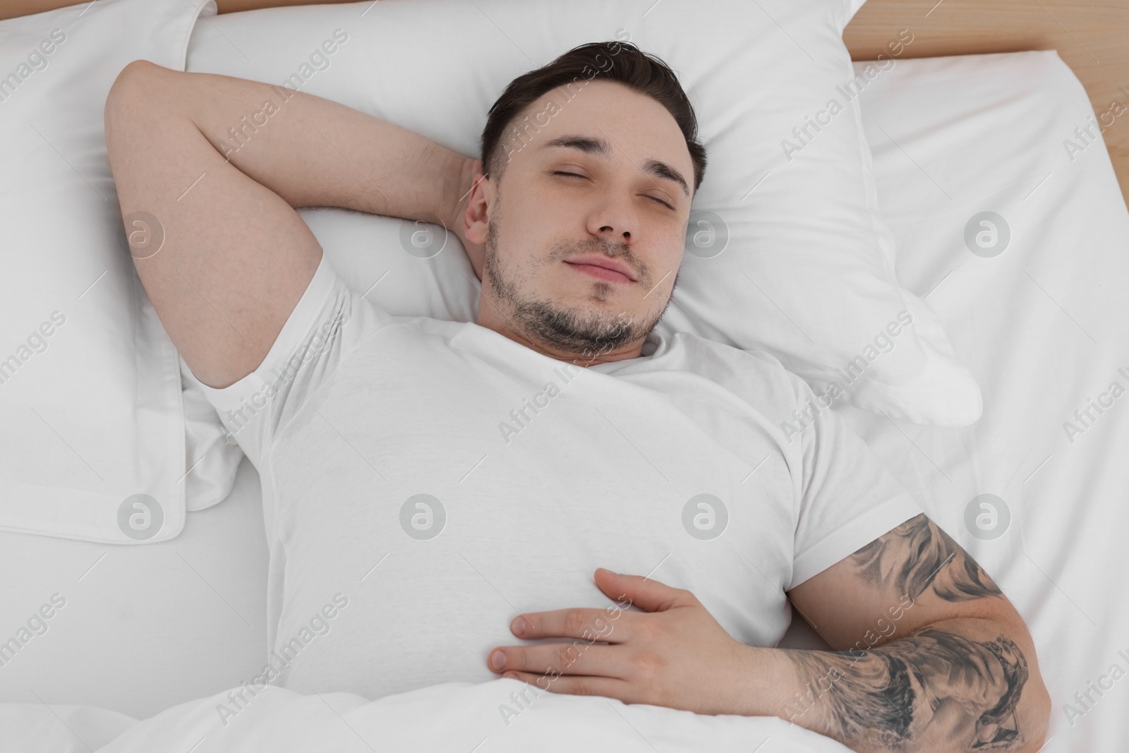 Photo of Bedtime. Handsome man sleeping in bed indoors, above view