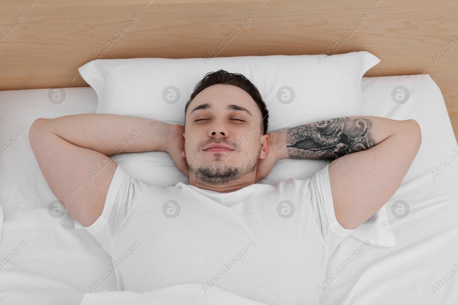 Photo of Bedtime. Handsome man sleeping in bed indoors, above view