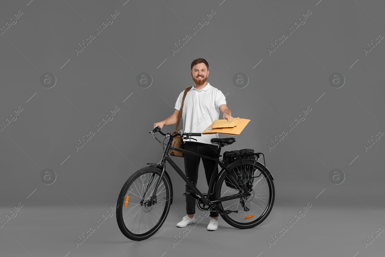 Photo of Postman with bicycle delivering letters on grey background