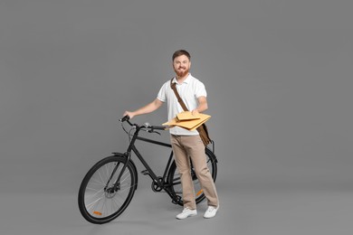 Photo of Postman with bicycle delivering letters on grey background
