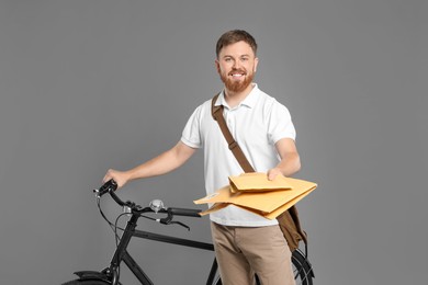 Photo of Postman with bicycle delivering letters on grey background