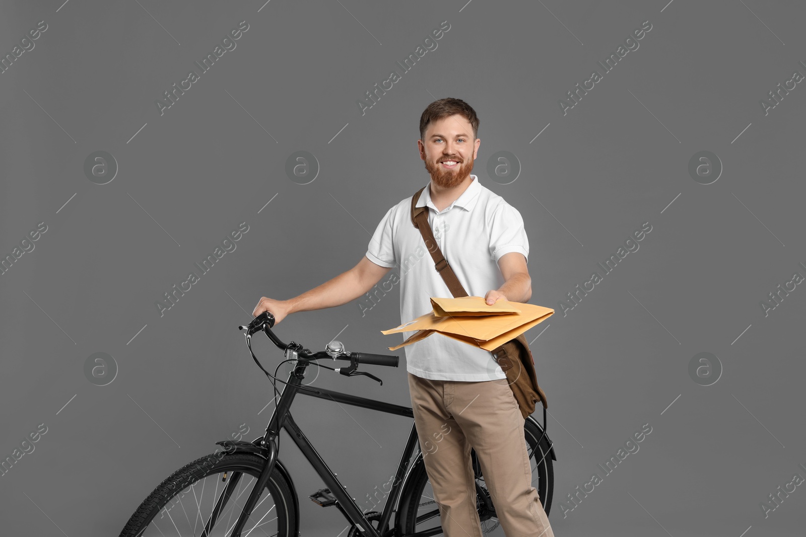 Photo of Postman with bicycle delivering letters on grey background