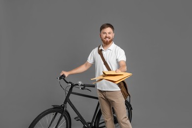 Postman with bicycle delivering letters on grey background