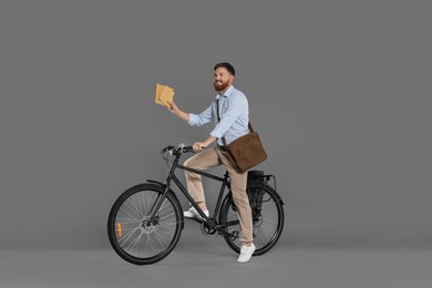 Postman on bicycle delivering letters against grey background